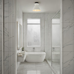 Sebastian Flush Mount light in a modern bathroom with marble walls and a freestanding tub.