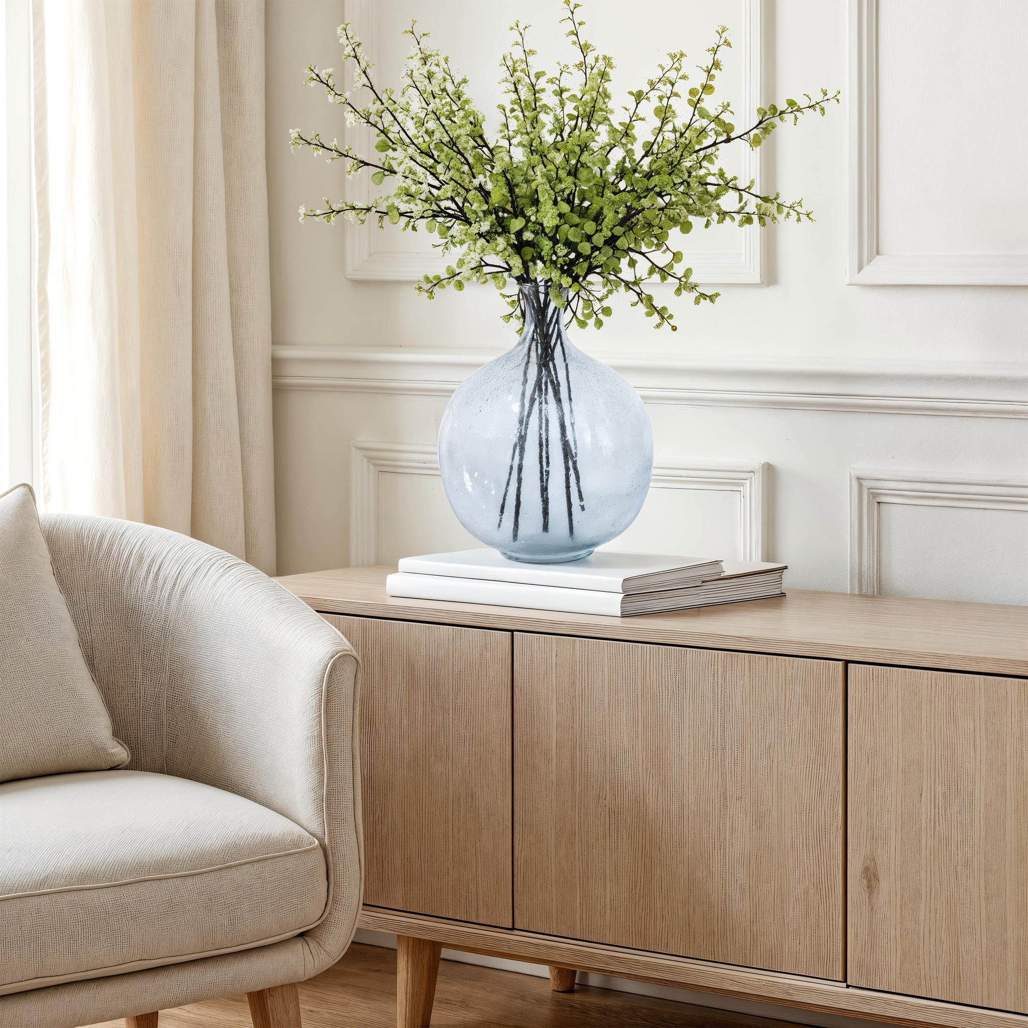 Mirabella vase by Renwil, styled with green branches, placed on a wooden cabinet
