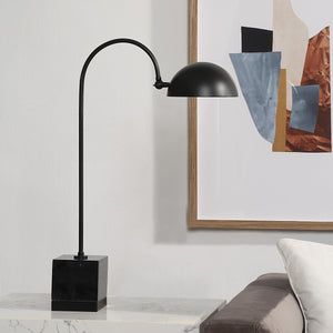 Sansia Table Lamp positioned beside a couch and artwork, showcasing its design.