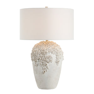 Wavy table lamp featuring a detailed white base and a white drum shade, illuminated