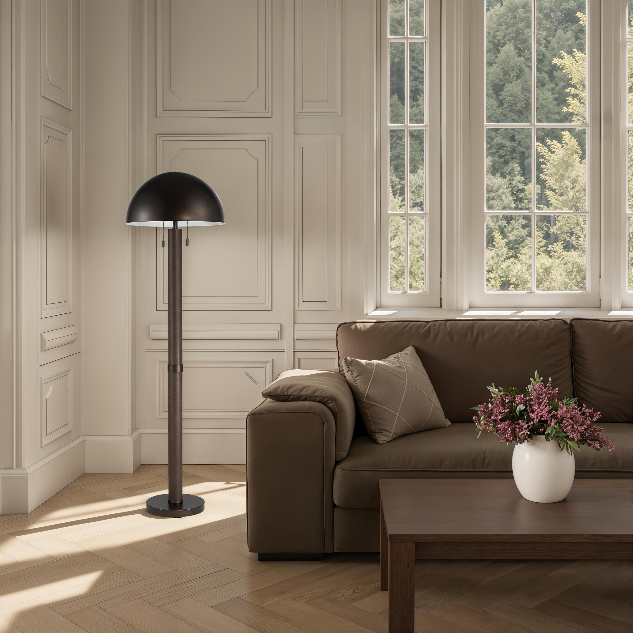 Incanta floor lamp in a stylish living room next to a brown sofa and large windows.