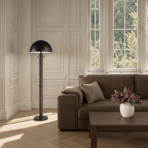 Incanta floor lamp in a stylish living room next to a brown sofa and large windows.